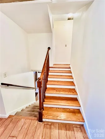 a view of a hallway with wooden floor and a bathroom