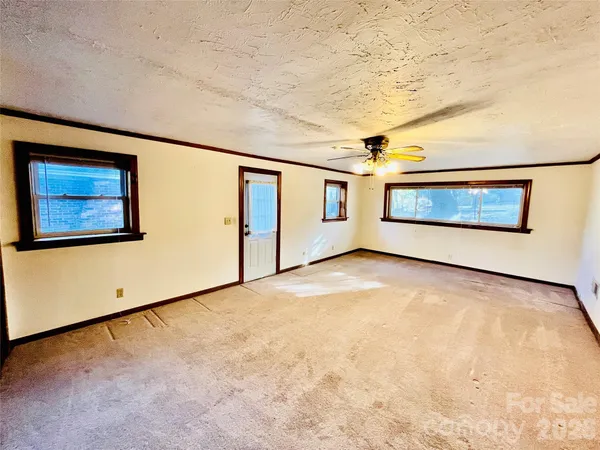 a view of an empty room with stairs and a ceiling fan