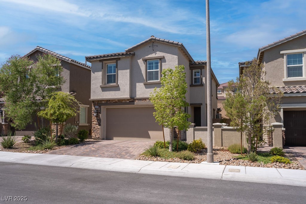 8099 Rams Collide Street Las Vegas, NV 89166 - Photo 18 of 72 Mediterranean / spanish home featuring a garage, driveway, stucco siding, a tiled roof, and stone siding