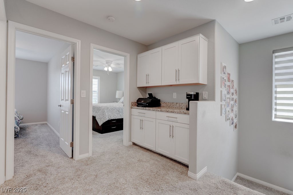 8099 Rams Collide Street Las Vegas, NV 89166 - Photo 42 of 72 Kitchen featuring light carpet, white cabinets, and light stone countertops
