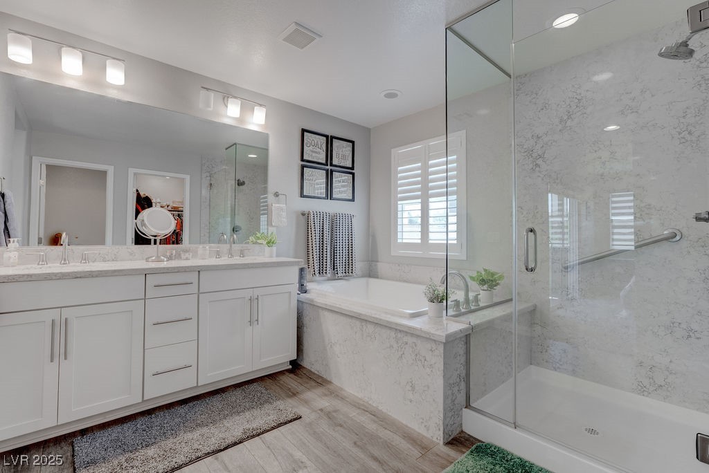 8099 Rams Collide Street Las Vegas, NV 89166 - Photo 50 of 72 Bathroom with a marble finish shower, a garden tub, double vanity, light wood-type flooring, and a spacious closet