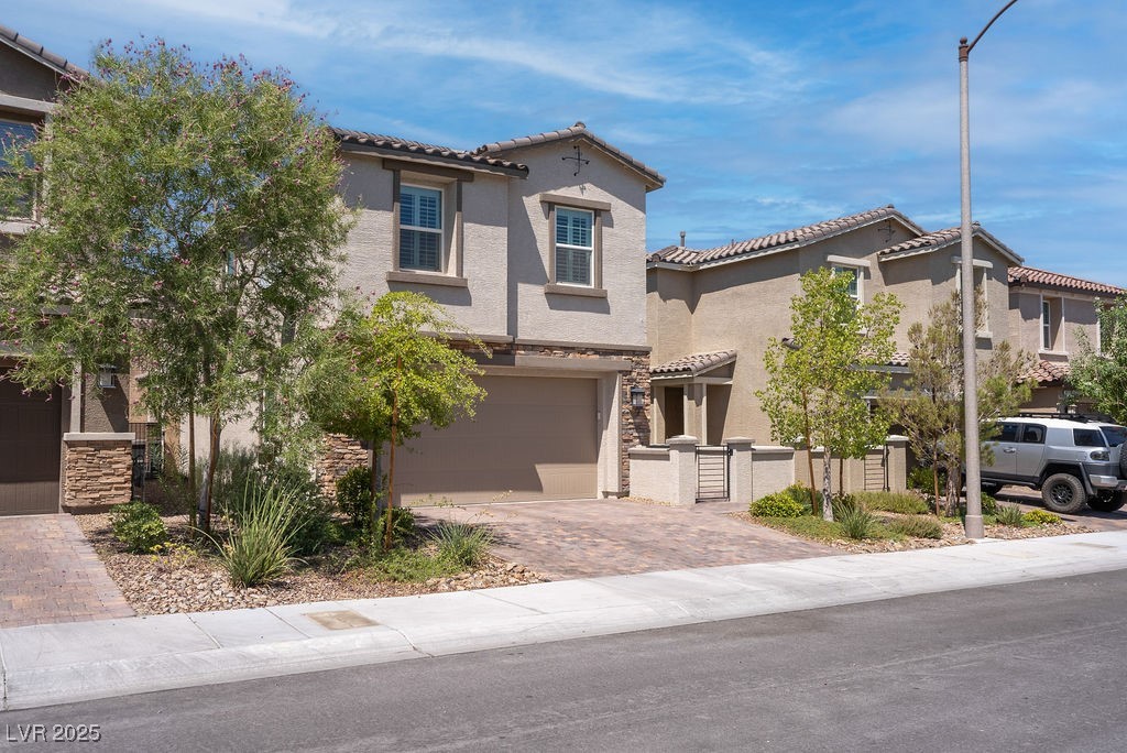 8099 Rams Collide Street Las Vegas, NV 89166 - Photo 65 of 72 Mediterranean / spanish house with decorative driveway, a garage, a tiled roof, stucco siding, and stone siding