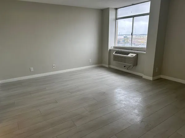 an empty room with wooden floor and windows
