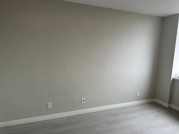 an empty room with wooden floor and window