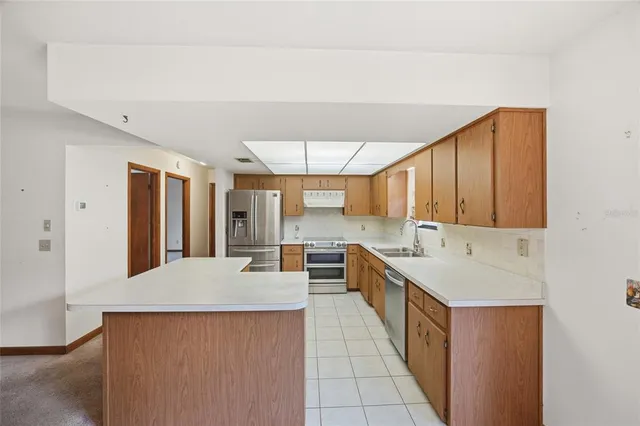 a large kitchen with kitchen island a sink stainless steel appliances wooden floor and cabinets