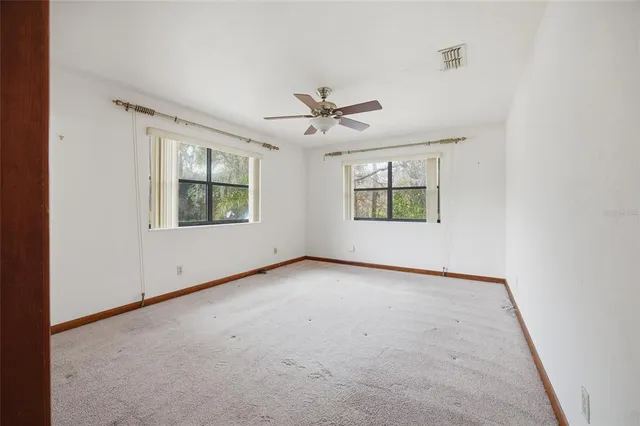 an empty room with windows and ceiling fan