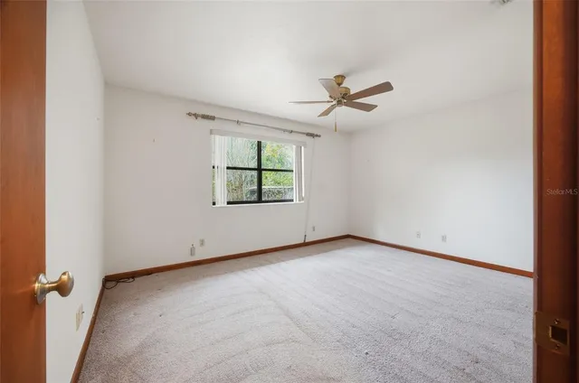 an empty room with windows and ceiling fan