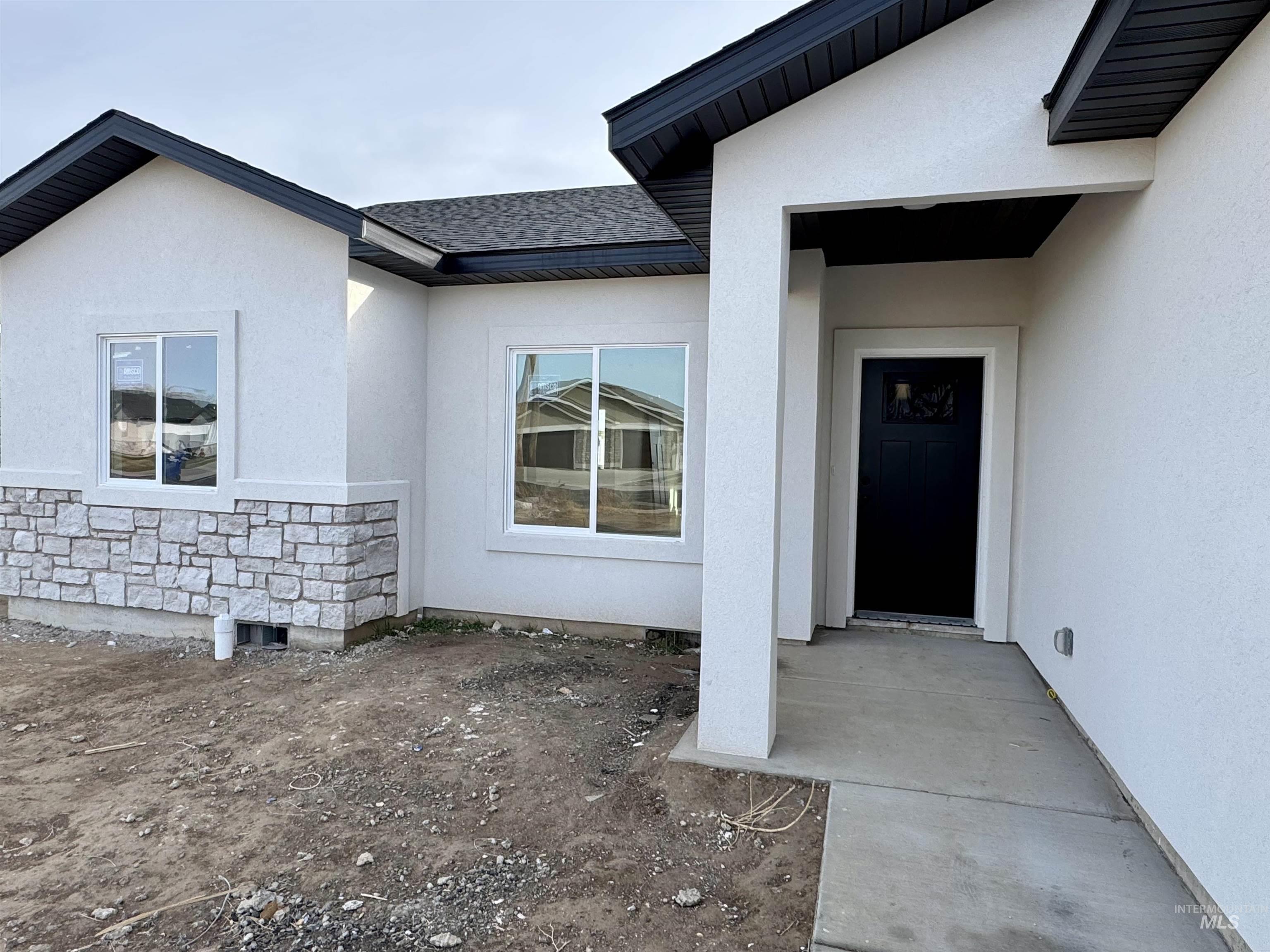 2014 Regan Street Jerome, ID 83338 - Photo 3 of 15 Doorway to property with stone siding, stucco siding, and roof with shingles