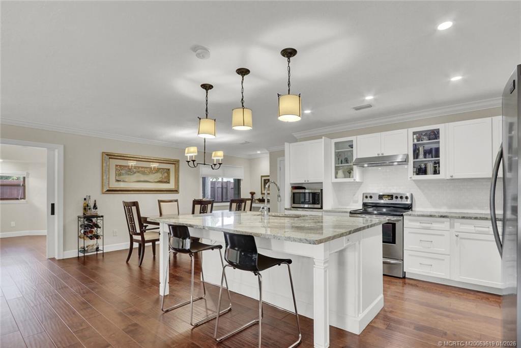 3060 Southeast Darien Road Port St. Lucie, FL 34952 - Photo 12 of 52 a kitchen with stainless steel appliances kitchen island granite countertop a table chairs stove and refrigerator