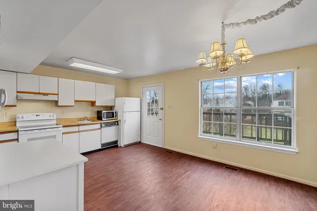 a kitchen with stainless steel appliances granite countertop a stove a sink dishwasher a refrigerator and a dining table with wooden floor