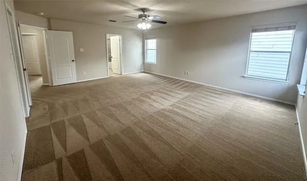 an empty room with windows and fan