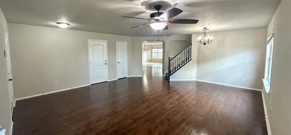 an empty room with wooden floor a kitchen view and a fireplace