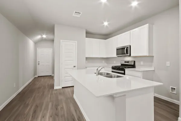 a kitchen with a sink a stove cabinets and wooden floor