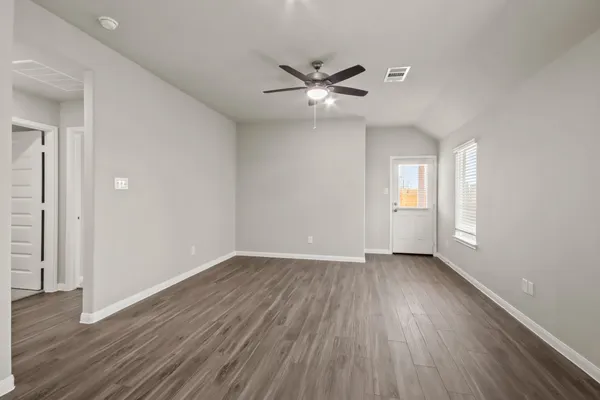 an empty room with wooden floor fan and windows