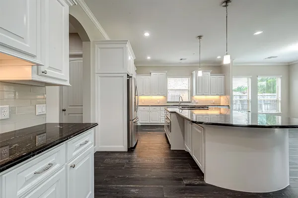 a large kitchen with granite countertop a large counter top a sink stainless steel appliances and cabinets