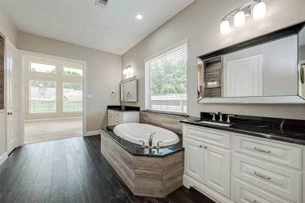 a spacious bathroom with a granite countertop tub sink and mirror