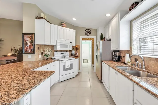 a kitchen with granite countertop a sink stove refrigerator and cabinets