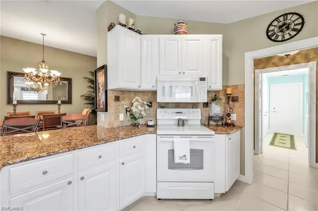 a kitchen with granite countertop white cabinets and white appliances