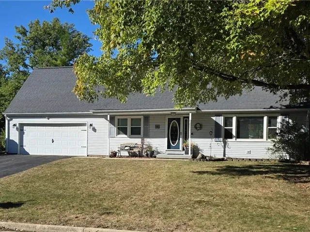 a front view of house with yard and trees in the background