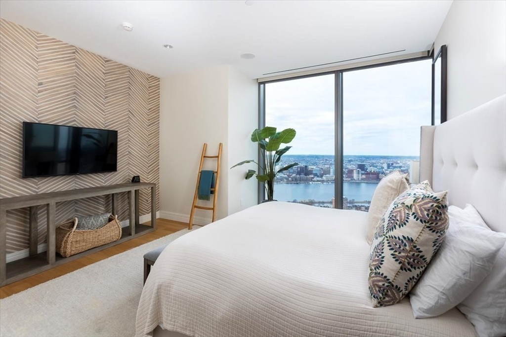 1 Dalton Street, Unit 5402 Boston, MA 02115 - Photo 12 of 17 a spacious bedroom with a large bed and a flat tv screen on dresser