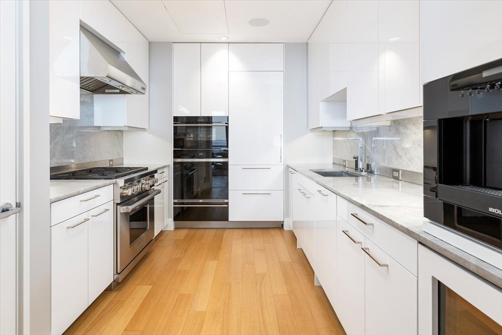 1 Dalton Street, Unit 5402 Boston, MA 02115 - Photo 8 of 17 a kitchen with kitchen island granite countertop a stove a sink and a refrigerator