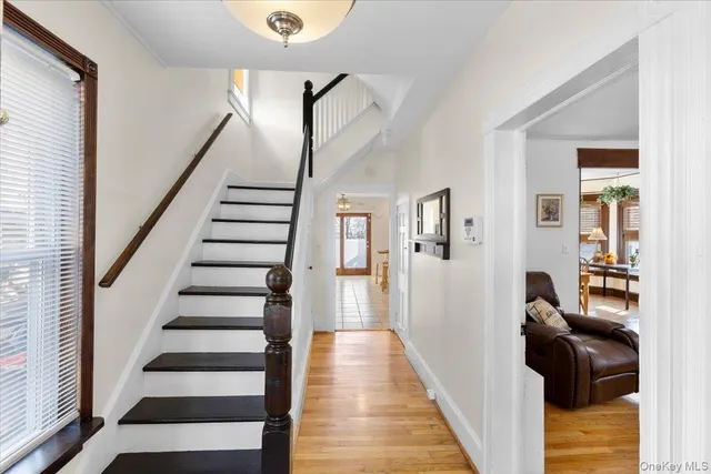 a view of a hallway to a livingroom with wooden floor and stairs