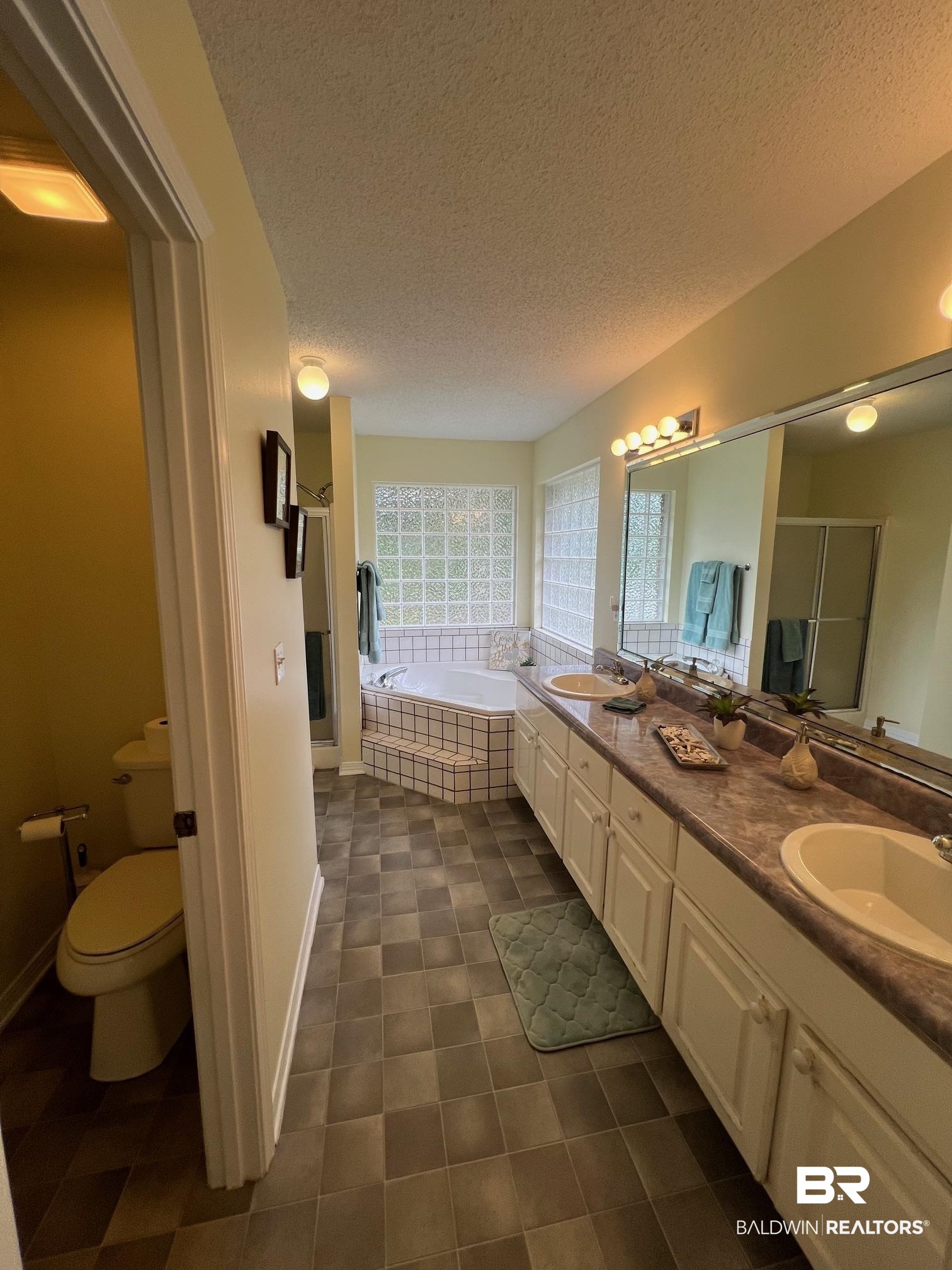 2204 Club House Drive Lillian, AL 36549 - Photo 12 of 38 Bathroom featuring a textured ceiling, a shower stall, double vanity, a garden tub, and tile patterned flooring