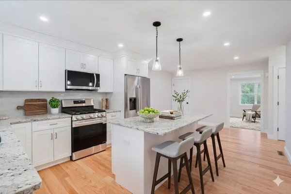 a kitchen with stainless steel appliances granite countertop a stove top oven a refrigerator a sink and chairs