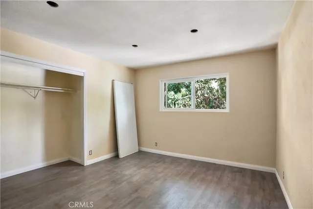 a view of a livingroom with wooden floor and a refrigerator