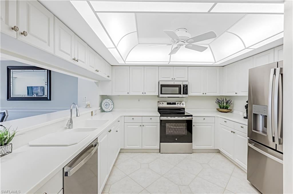 21 Bluebill Avenue, Unit B503 Naples, FL 34108 - Photo 15 of 40 a kitchen with stainless steel appliances granite countertop a sink and dishwasher a refrigerator with white cabinets
