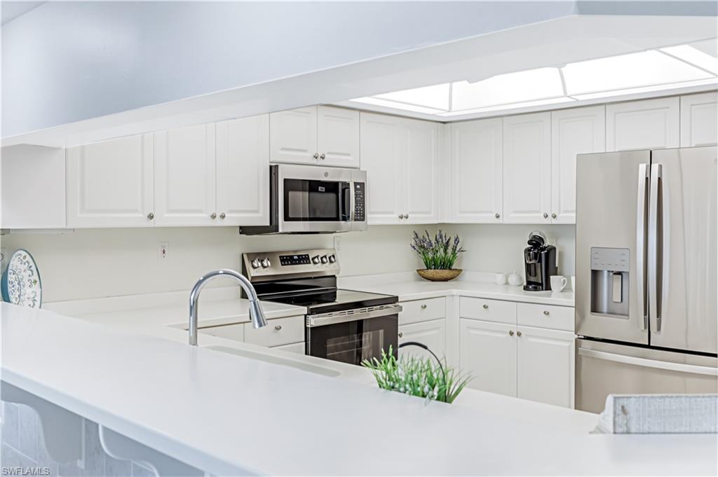 21 Bluebill Avenue, Unit B503 Naples, FL 34108 - Photo 18 of 40 a kitchen with stainless steel appliances a white cabinets wooden floors and white cabinets