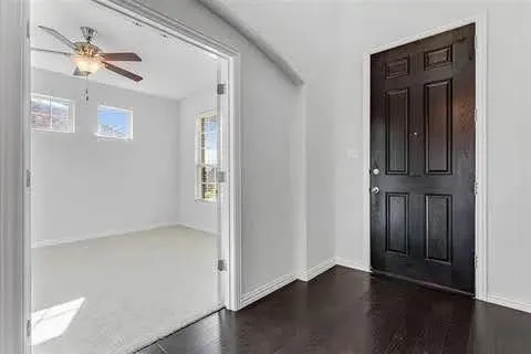 an empty room with wooden floor closet and windows
