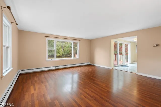 a view of an empty room with a window and wooden floor