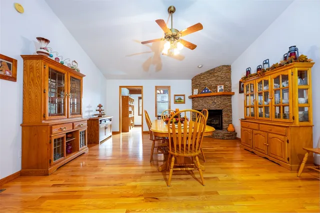 a living room with stainless steel appliances kitchen island granite countertop a refrigerator a stove a oven and a dining table with wooden floor