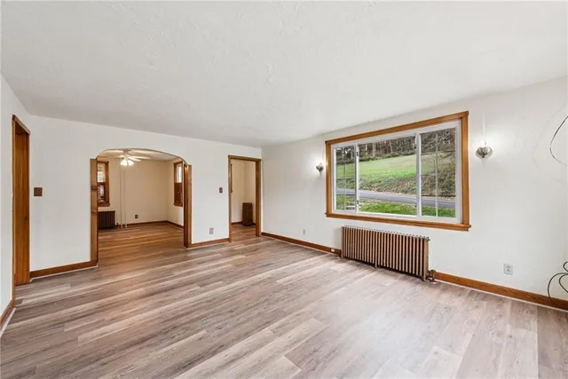 an empty room with wooden floor and windows