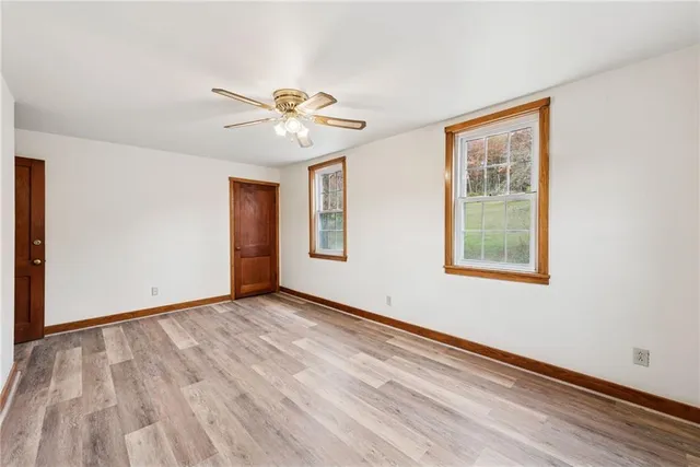 an empty room with windows and fan
