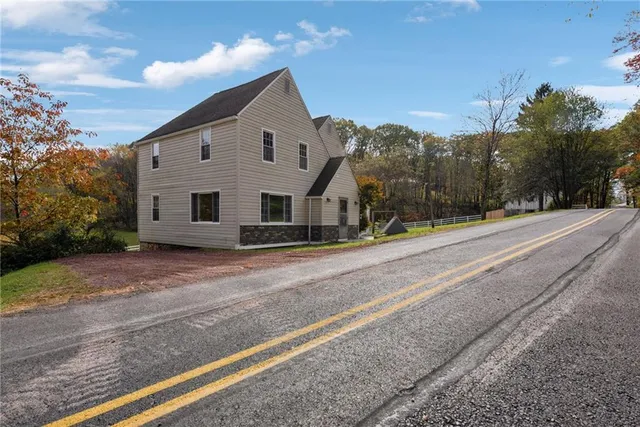 a view of a house with a big yard potted plants and a bench