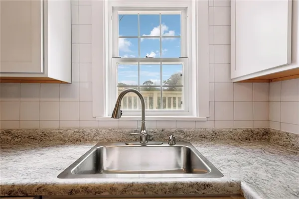 a kitchen with granite countertop a refrigerator a sink and white cabinets