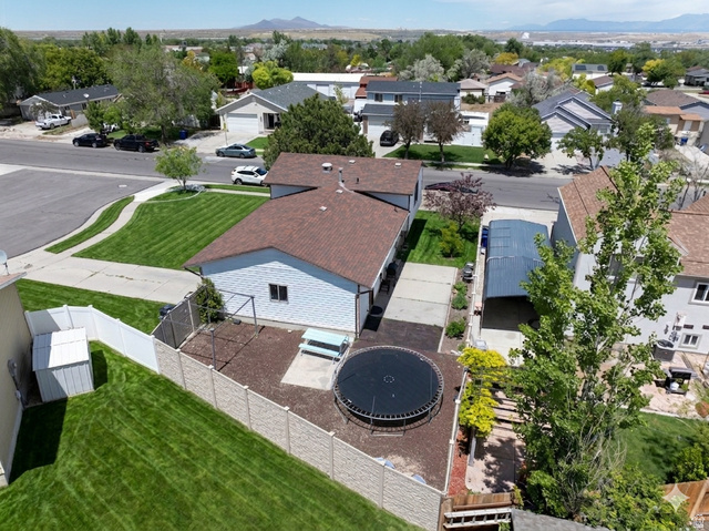 3689 Lasso Loop Circle Magna, UT 84044 - Photo 26 of 26 Ai enhanced Aerial view of thel property featuring a white vinyl-sided structure with a brown shingle roof, a paved driveway, and an attached carport