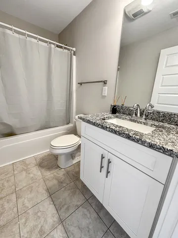 a bathroom with a granite countertop sink toilet and a mirror