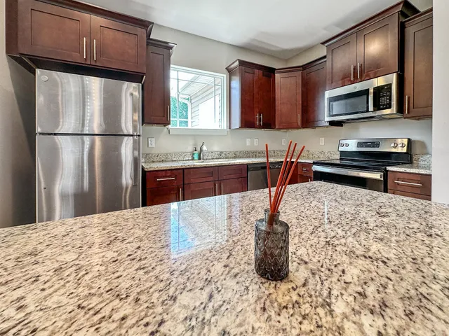 a kitchen with stainless steel appliances granite countertop a refrigerator sink stove and microwave