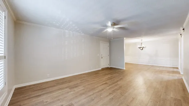 an empty room with wooden floor and fan