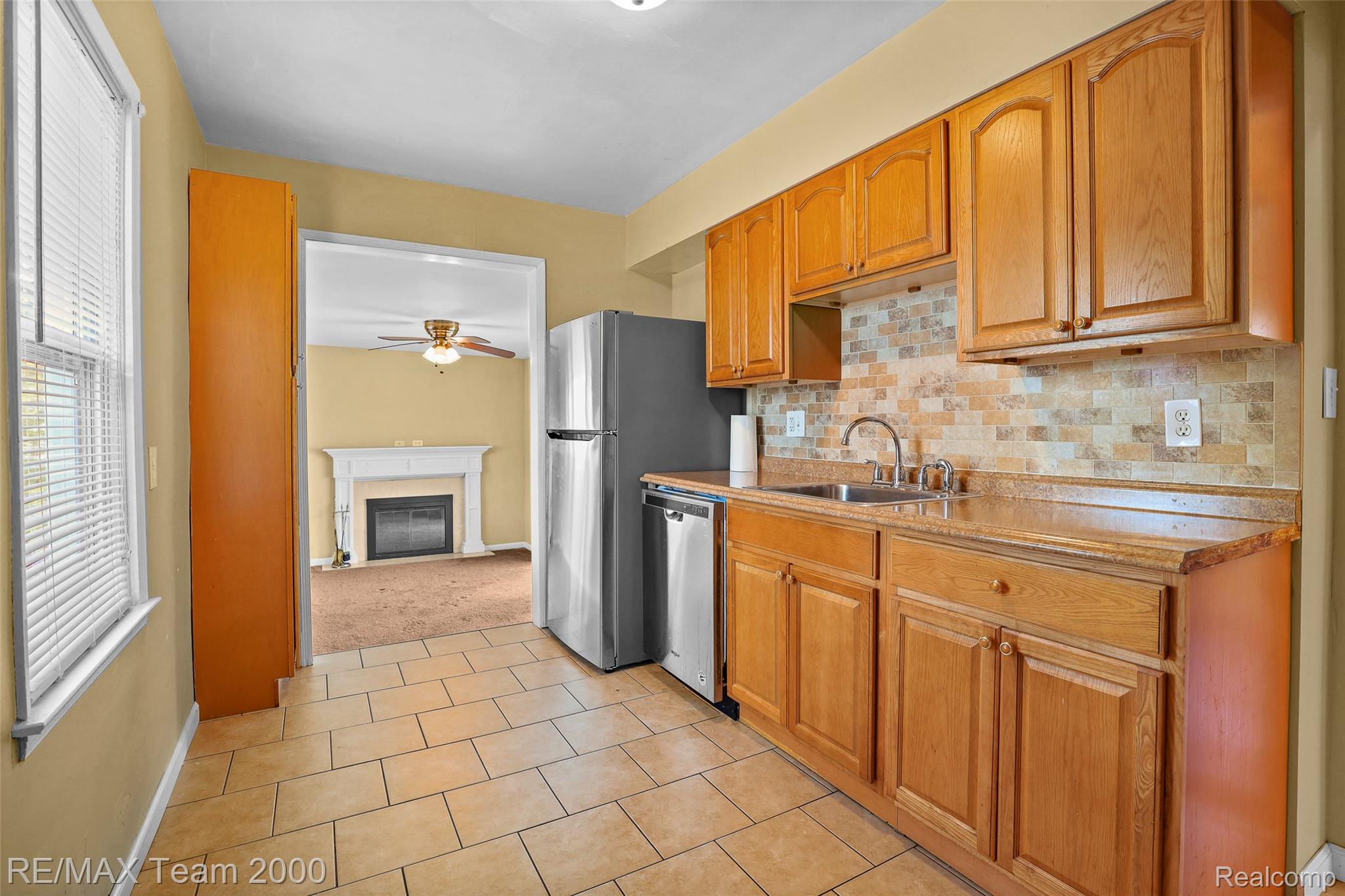 3130 Chestnut Street Dearborn, MI 48124 - Photo 7 of 30 Kitchen featuring wood-finish cabinetry, tile flooring, stone-look countertops, a stainless steel sink with a gooseneck faucet, and a decorative tile backsplash