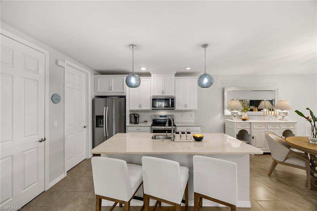 14610 Edgewater Circle Naples, FL 34114 - Photo 13 of 38 a kitchen with stainless steel appliances kitchen island granite countertop a dining table chairs and a refrigerator