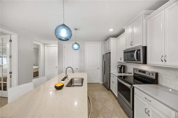 a kitchen with stainless steel appliances kitchen island granite countertop a sink a stove and a wooden floors