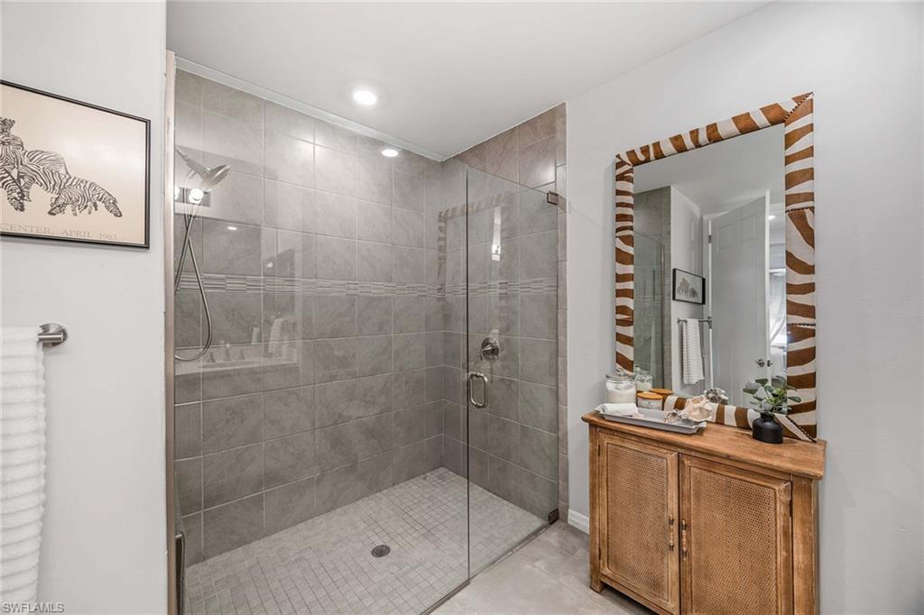 14610 Edgewater Circle Naples, FL 34114 - Photo 20 of 38 a bathroom with a shower a mirror and a sink