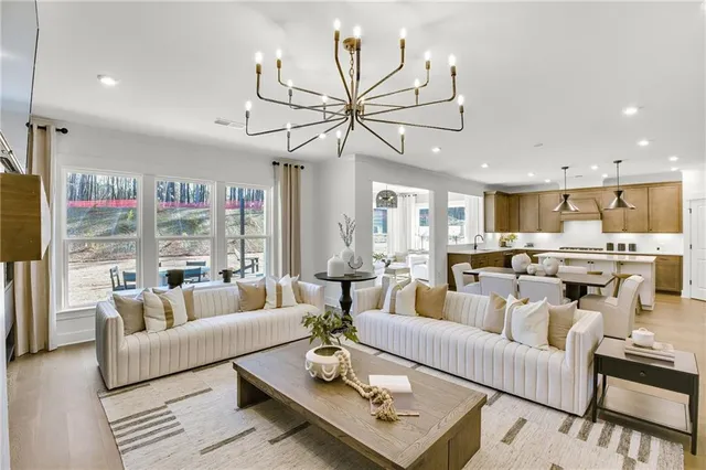 a living room with furniture kitchen view and a chandelier