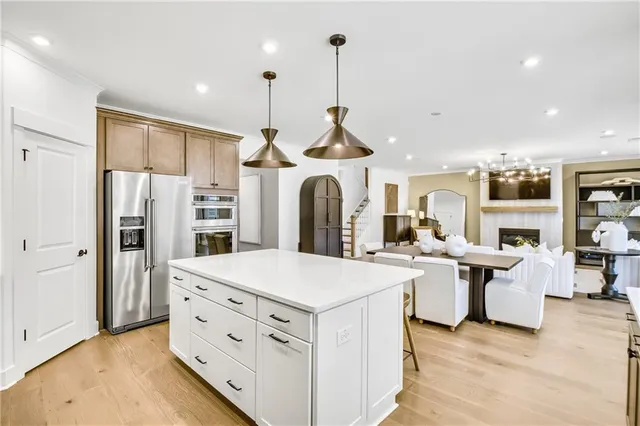 a kitchen with stainless steel appliances kitchen island granite countertop a stove a refrigerator a oven and white cabinets with wooden floor