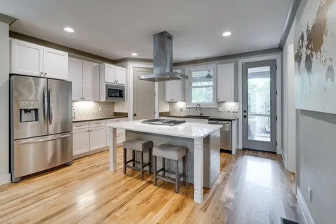 a kitchen with kitchen island granite countertop a sink appliances and cabinets