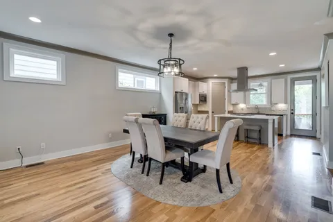 a dining room with wooden floor a chandelier a wooden table and chairs
